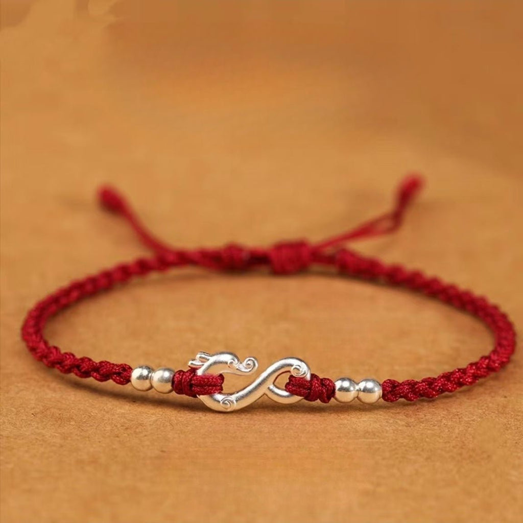 Bracelet en fil rouge ciré tressé avec pendentif infini et dragon en métal argenté, perles argentées.