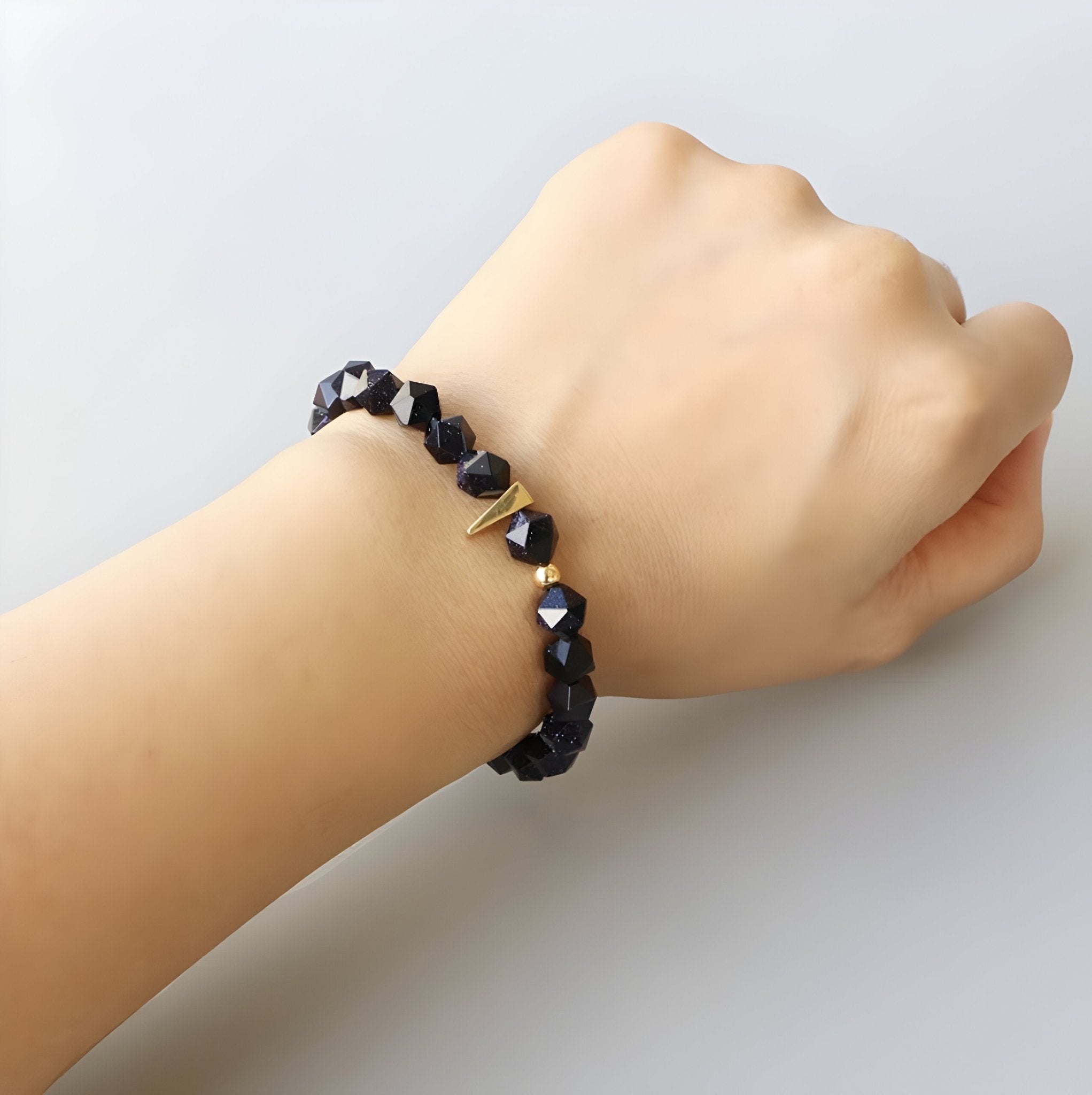 Bracelet mixte en grès bleu avec perles facettées et détail doré porté au poignet.