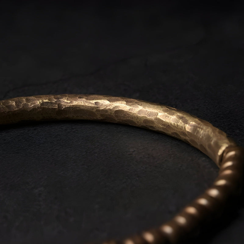 Bracelet en laiton martelé avec petites perles rondes finition marron sur fond noir.