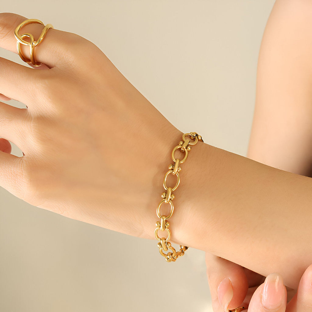 Bracelet en maille marine dorée en titane plaqué or sur poignet féminin avec bague assortie.