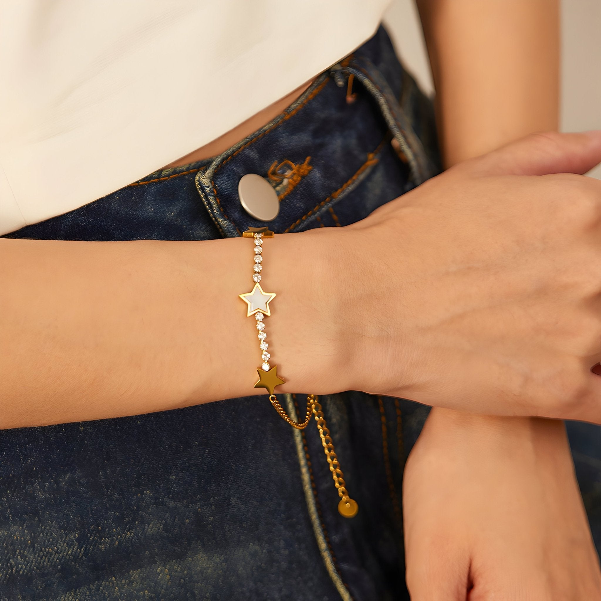 Bracelet fin en maille or avec étoiles brillantes en acier inoxydable porté au poignet féminin.