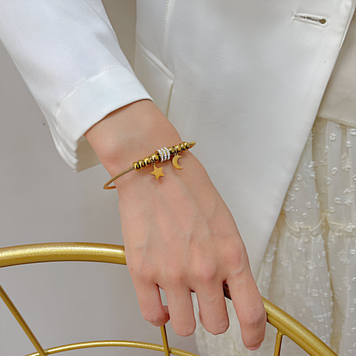 Bracelet serpent fin en acier inoxydable doré avec pendentifs lune et étoile scintillants.