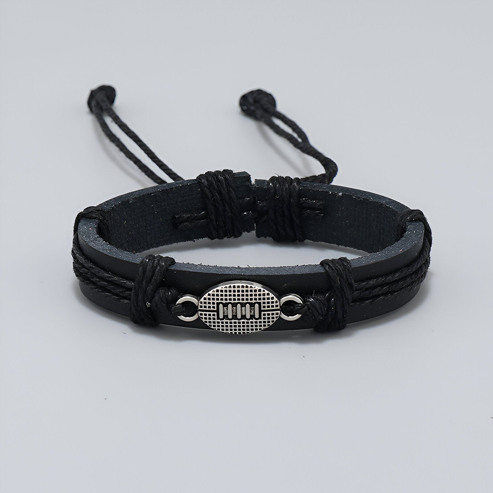 Bracelet noir en microfibre avec pendentif en forme de ballon de rugby argenté, fermeture réglable.