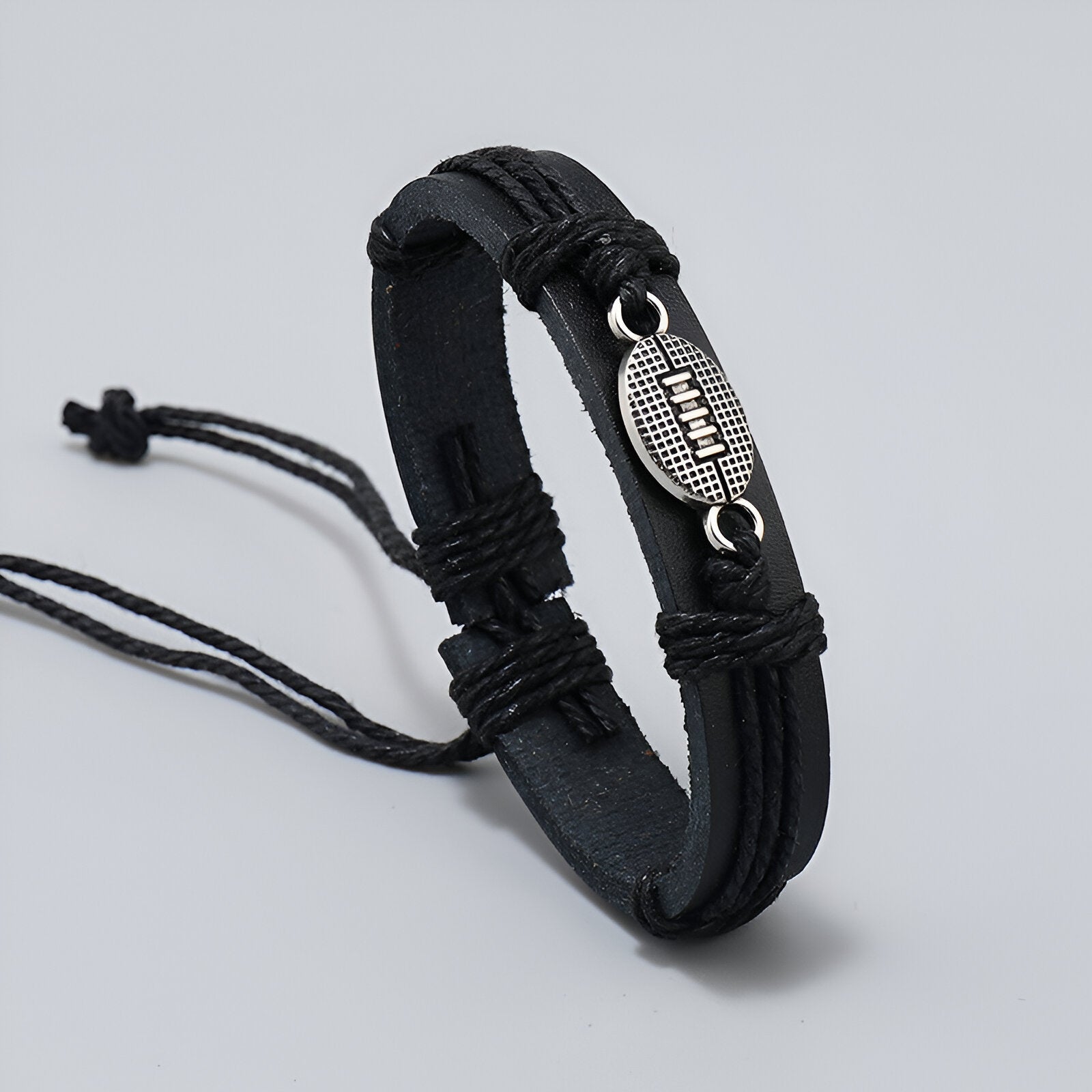Bracelet homme en microfibre noir avec pendentif en forme de ballon de rugby argenté.