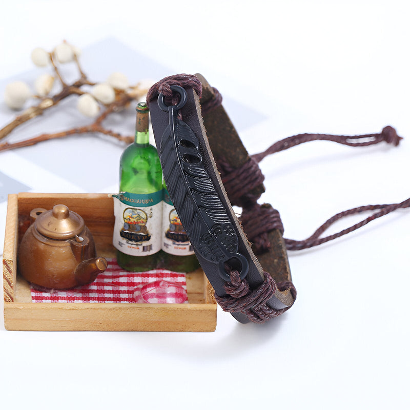 Bracelet large en microfibre marron avec motif grande plume embossé et réglage par cordon noir.