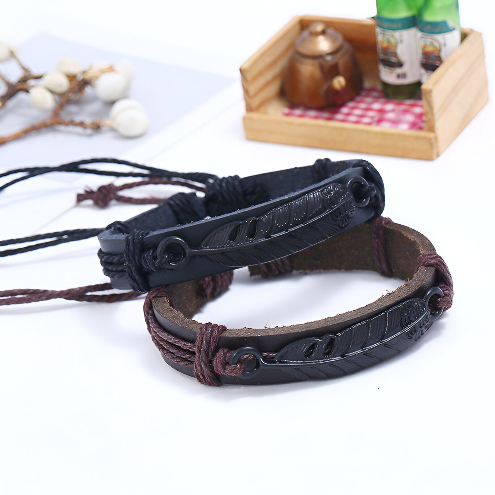 Bracelet mixte en microfibre noir avec grande plume en relief, fermé par cordon ajustable marron et noir.