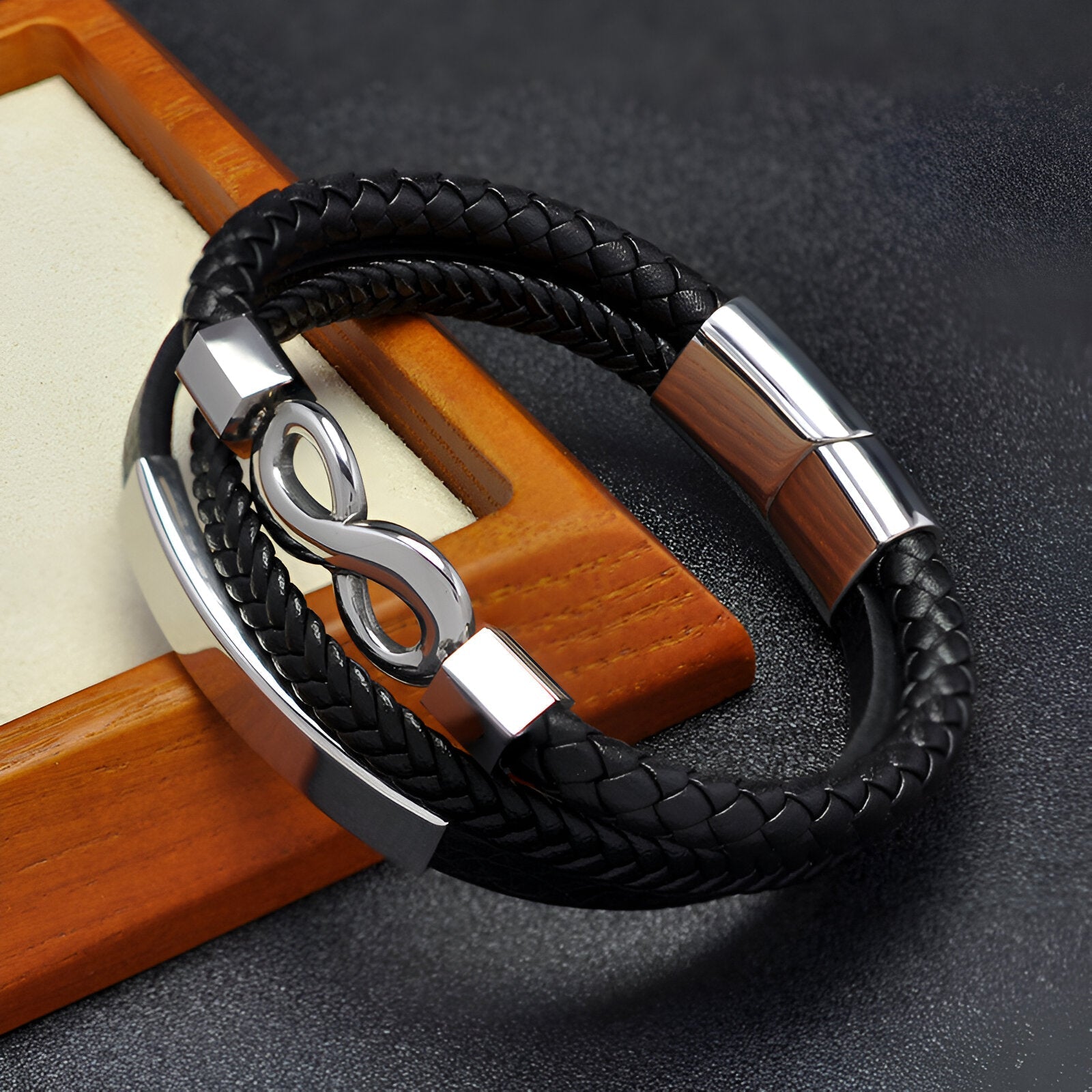 Bracelet multi-rangs noir en microfibre tressée avec motif infini en métal argenté.
