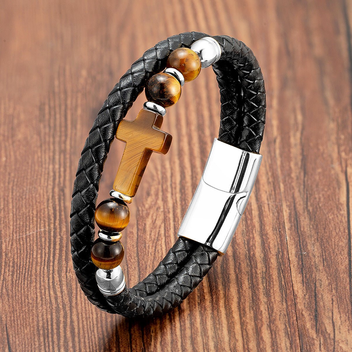 Bracelet en microfibre noire tressée avec perles œil de tigre et croix chrétienne en pierre, fermoir métallique argenté.