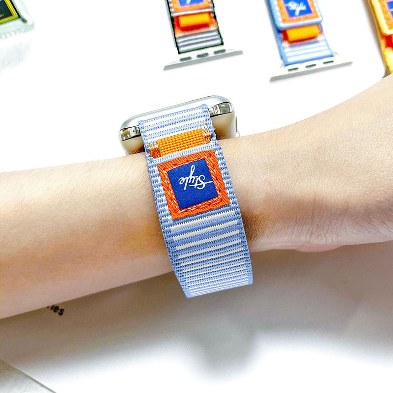 Bracelet en nylon gris clair rayé avec patch orange et bleu, ajustable pour Apple Watch.