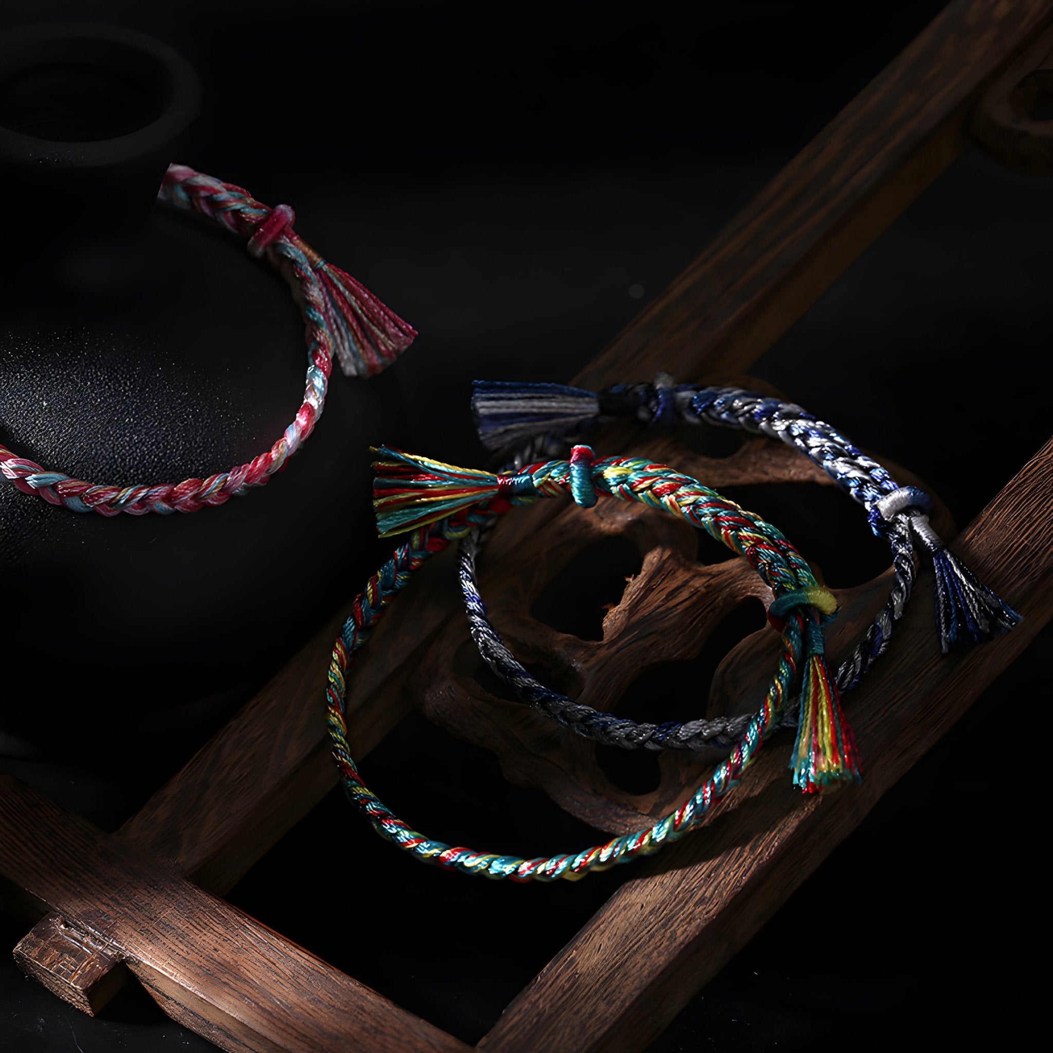 Trois bracelets en nylon tressé multicolore avec nœuds ajustables et franges colorées.