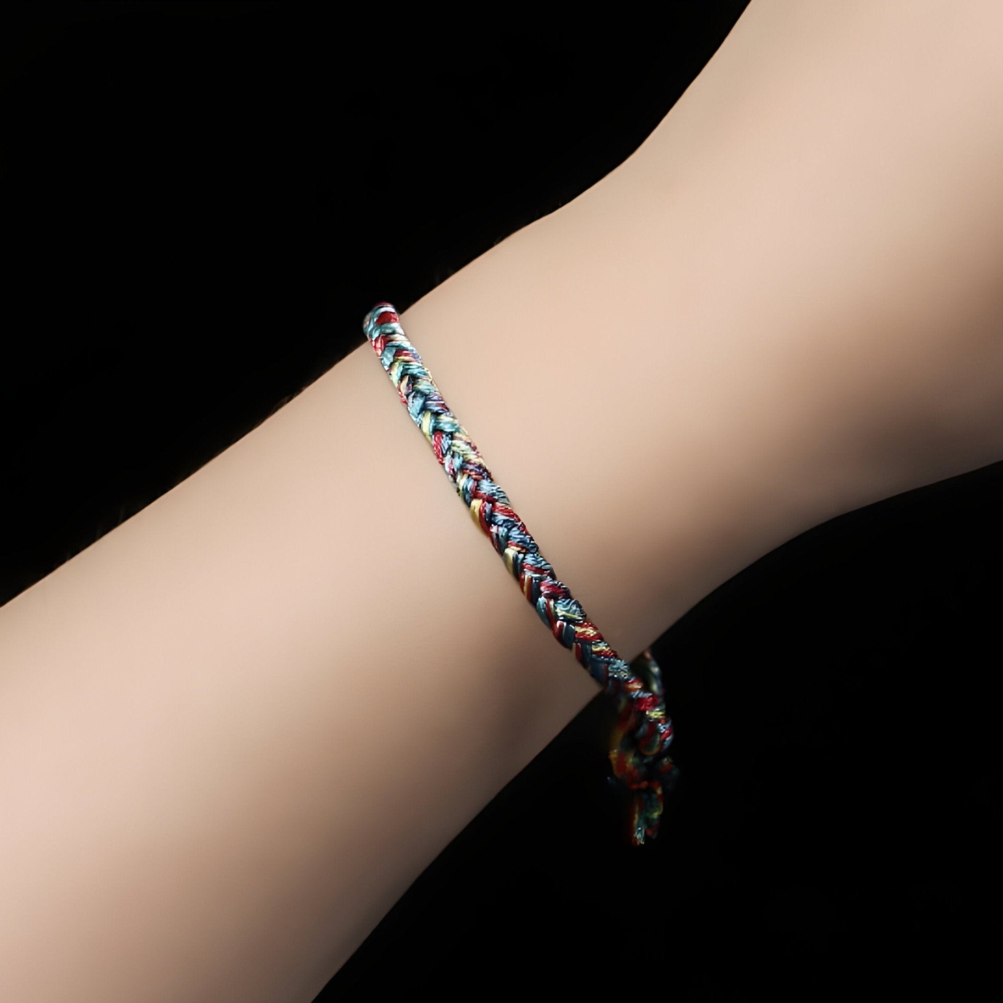 Bracelet en nylon tressé multicolore avec nuances de rose, bleu et blanc, style fin et ajustable sur poignet féminin.
