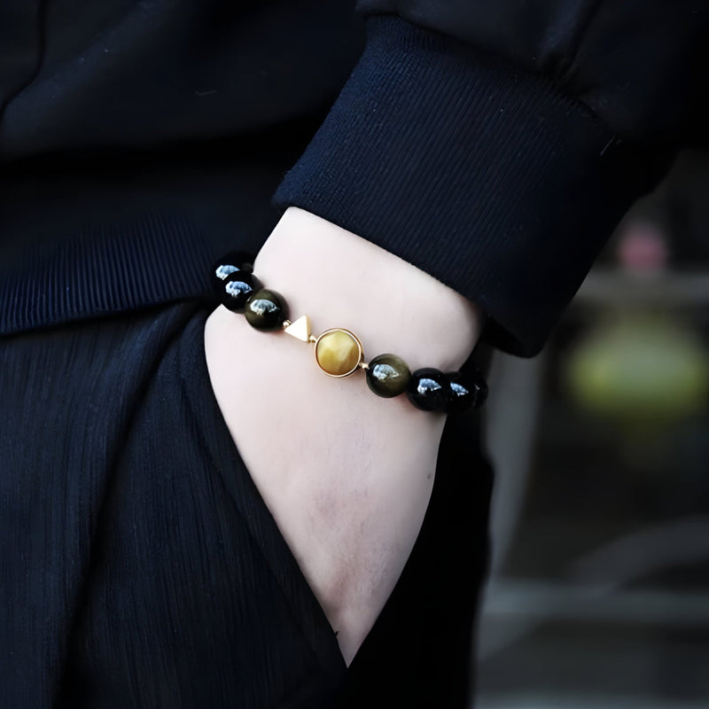 Bracelet mixte en perles noires d'obsidienne avec perle jaune d'œil de tigre au centre.