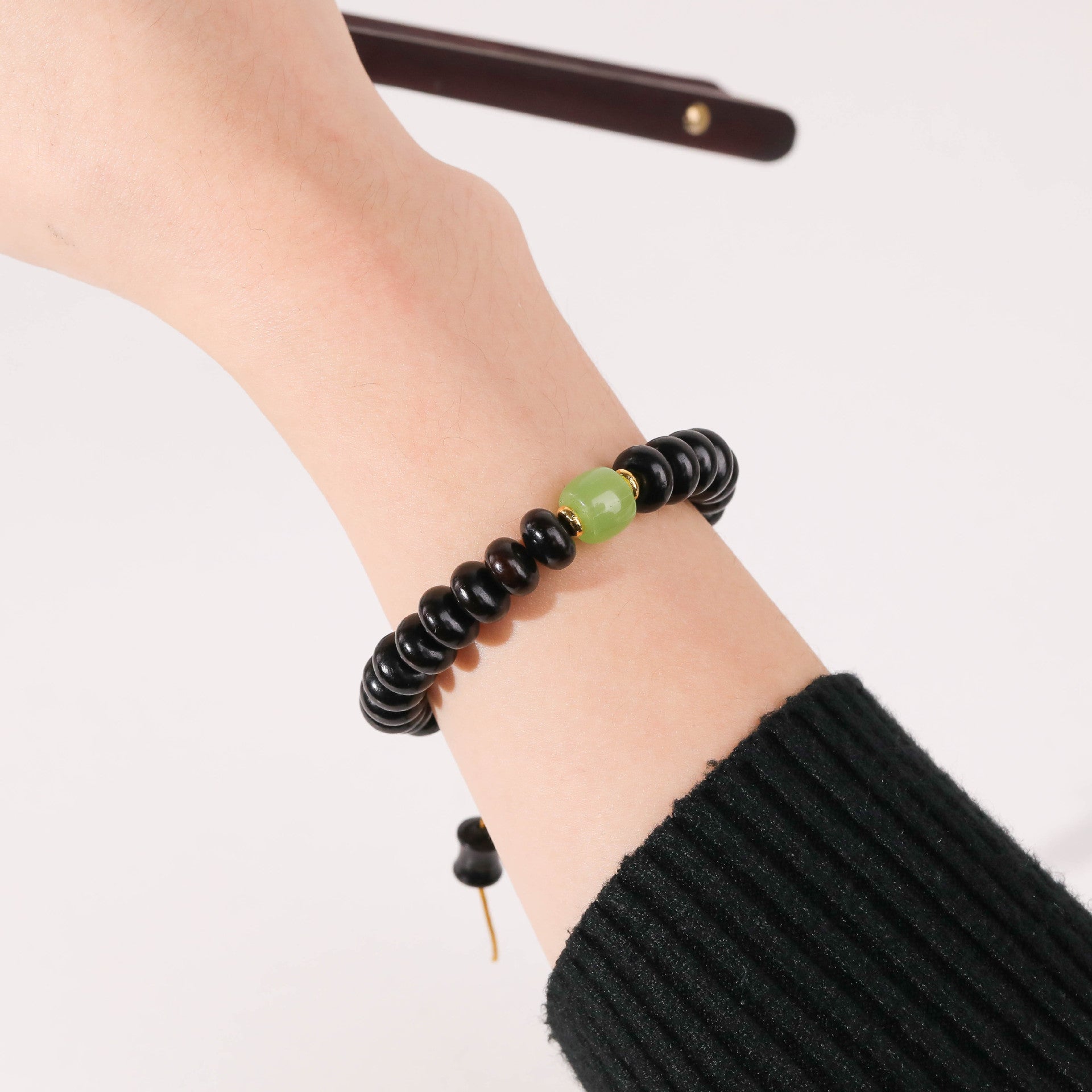 Bracelet femme perles bois santal noir et perle centrale verre vert éclatant.