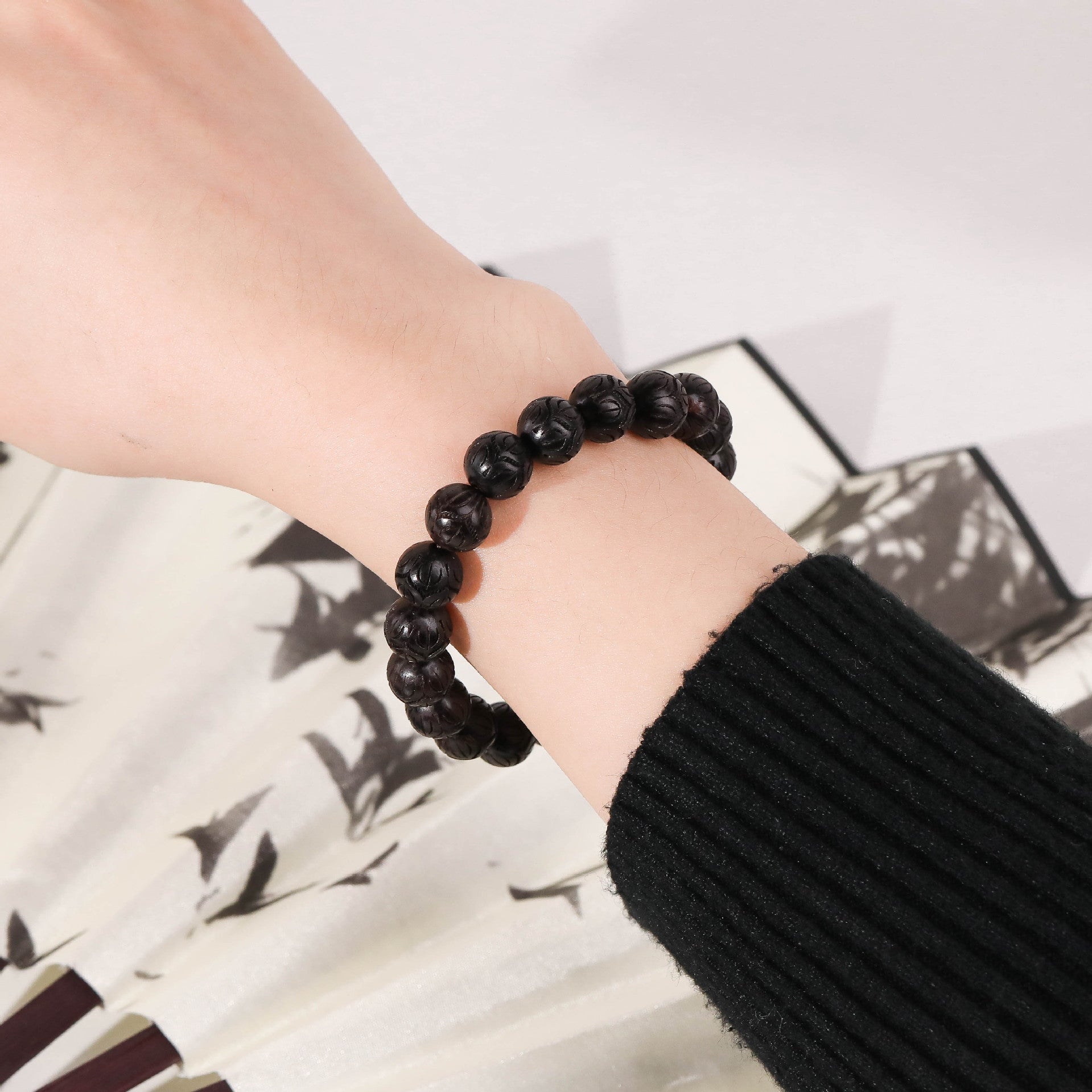 Bracelet en perles rondes de bois d'ébène noir porté sur un poignet, style minimaliste.