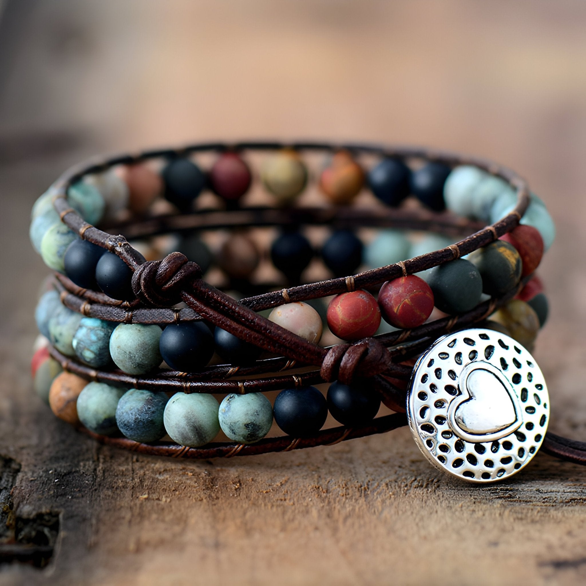 Bracelet multi-rangs en perles de jaspe multicolores avec fermoir bouton coeur argenté sur cuir marron.