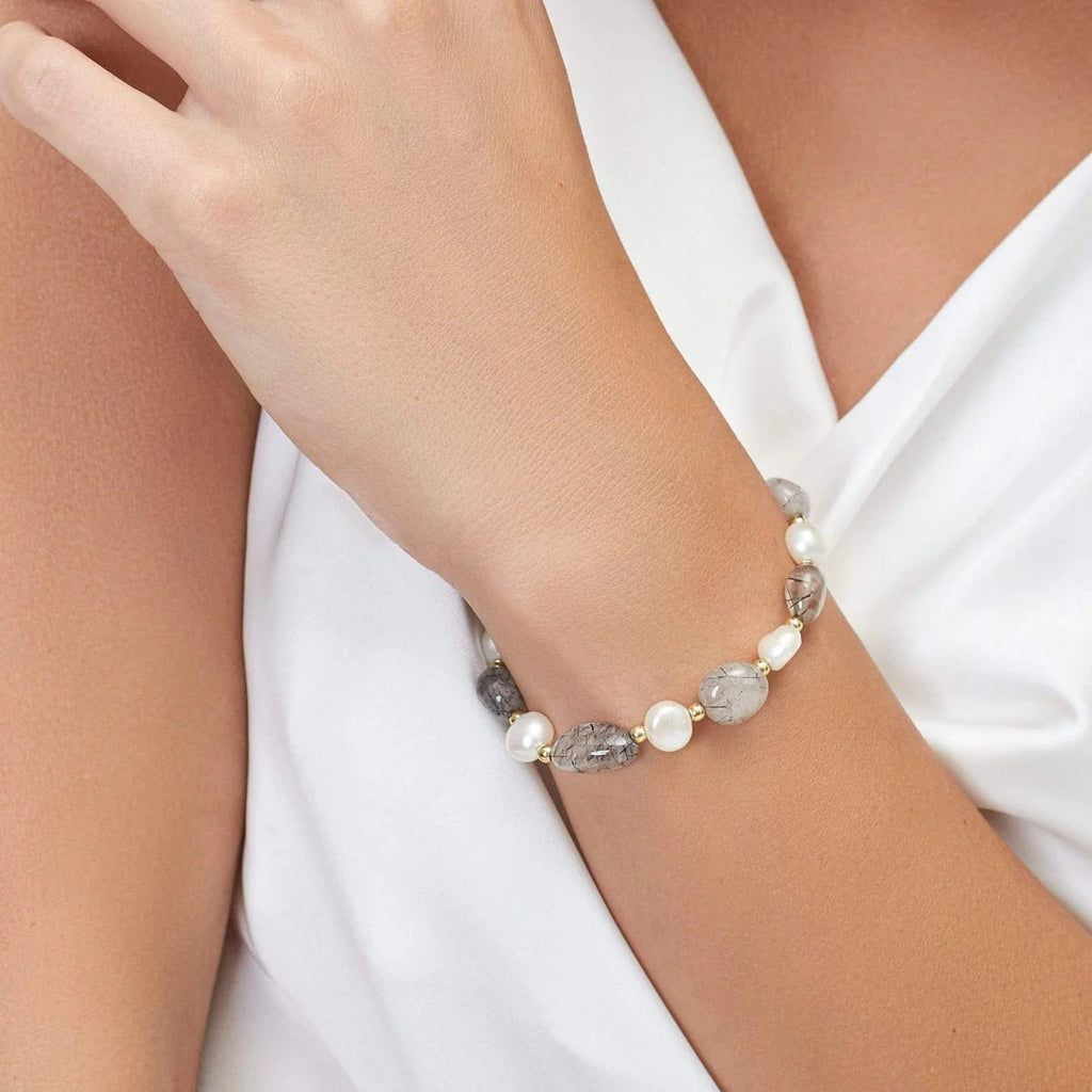 Bracelet ajustable avec perles d'eau douce blanches et pierres grises, style élégant et féminin.