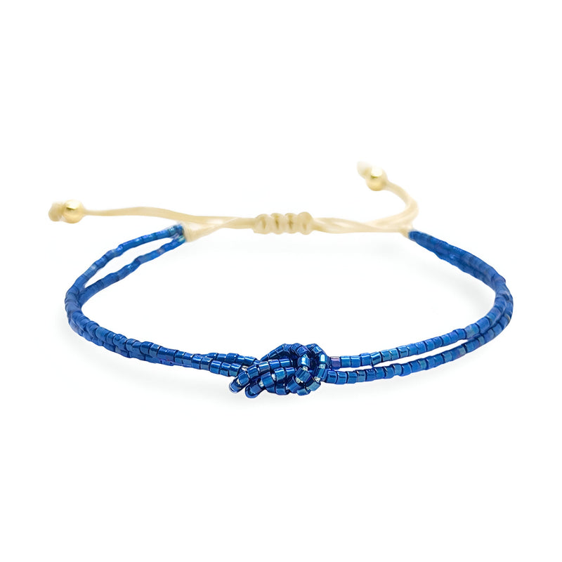 Bracelet bleu en perles japonaises avec nœud central et cordon beige réglable.