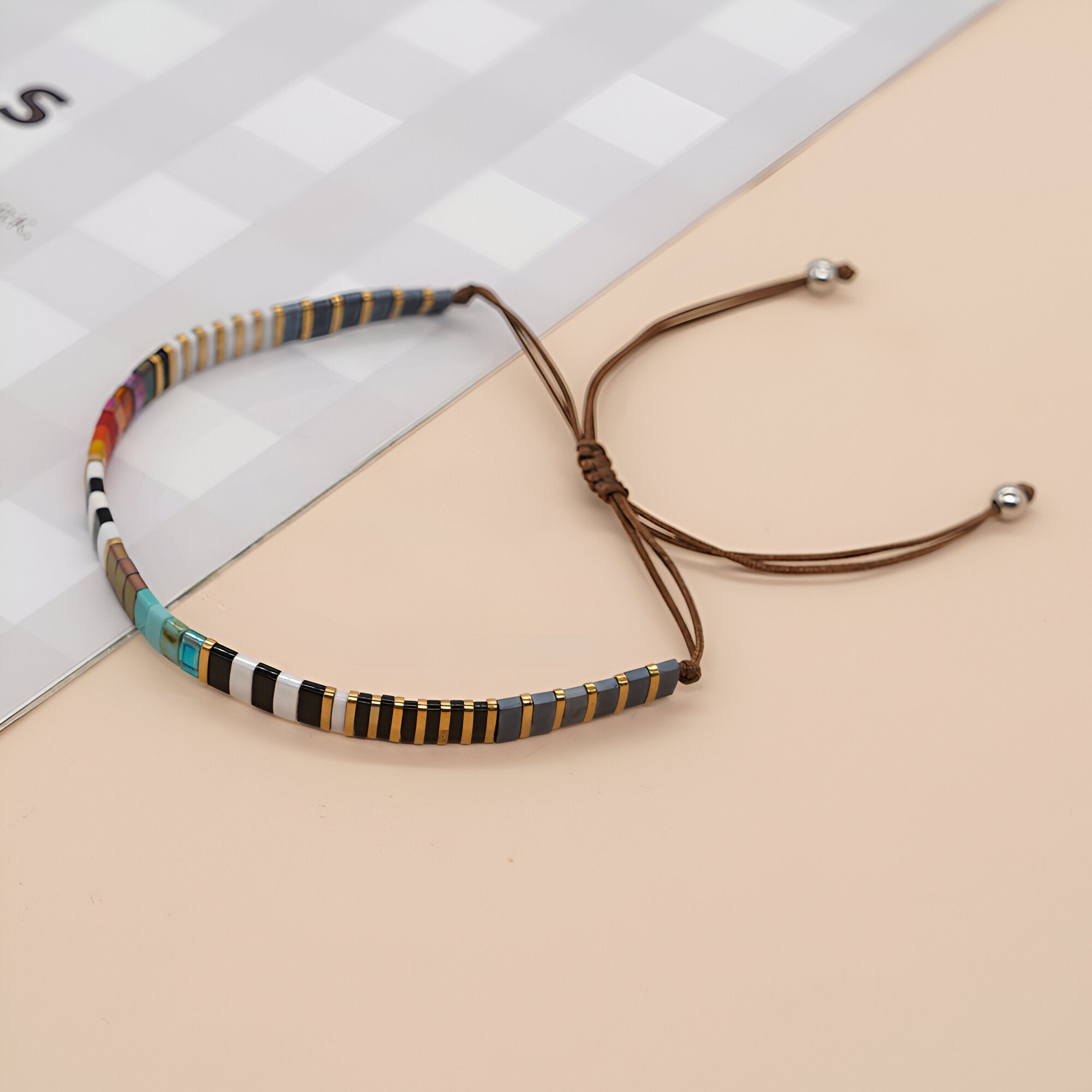 Bracelet ajustable en perles multicolores du Japon avec cordon marron et embouts argentés.