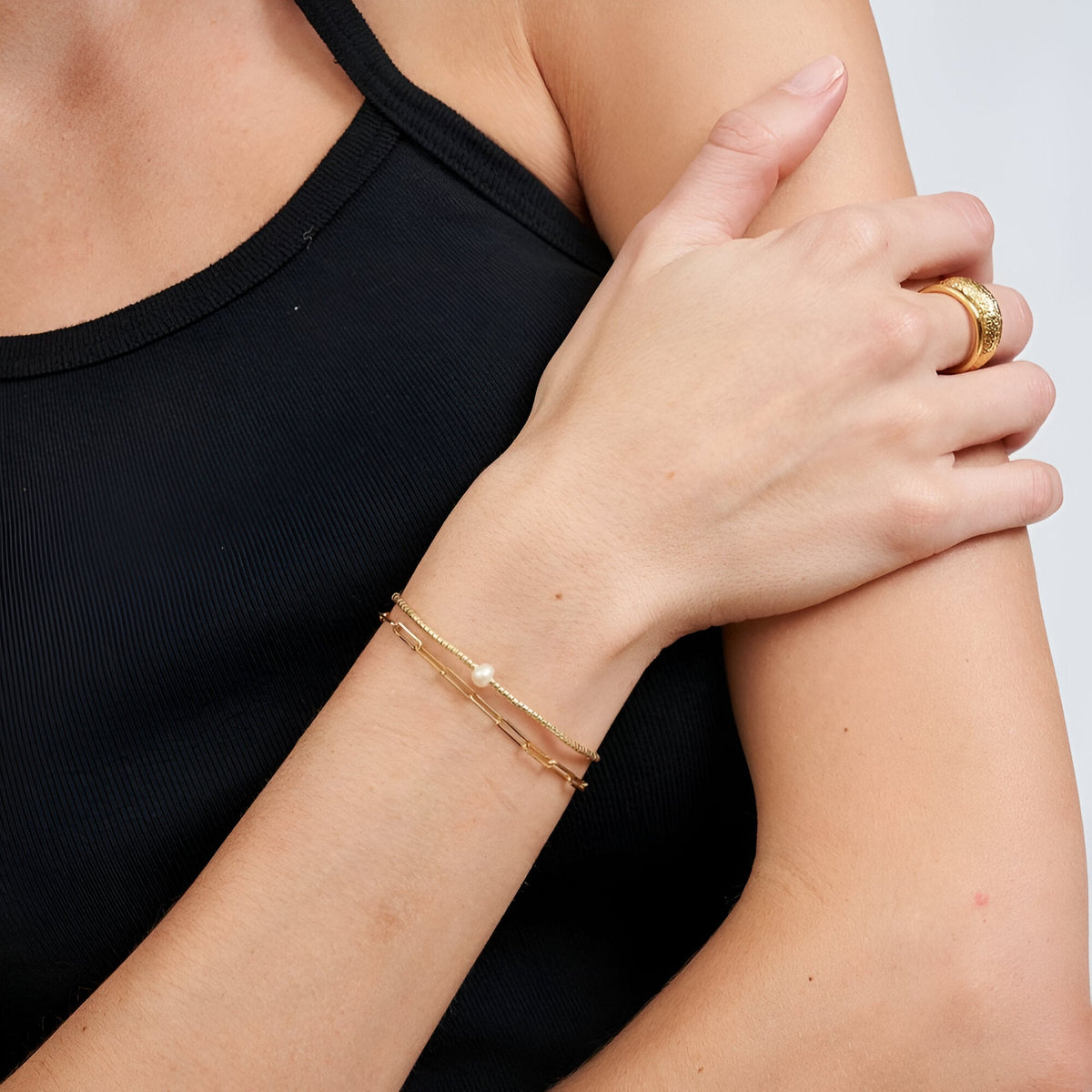 Bracelet fin en perles dorées japonaises avec petites perles blanches sur poignet féminin.