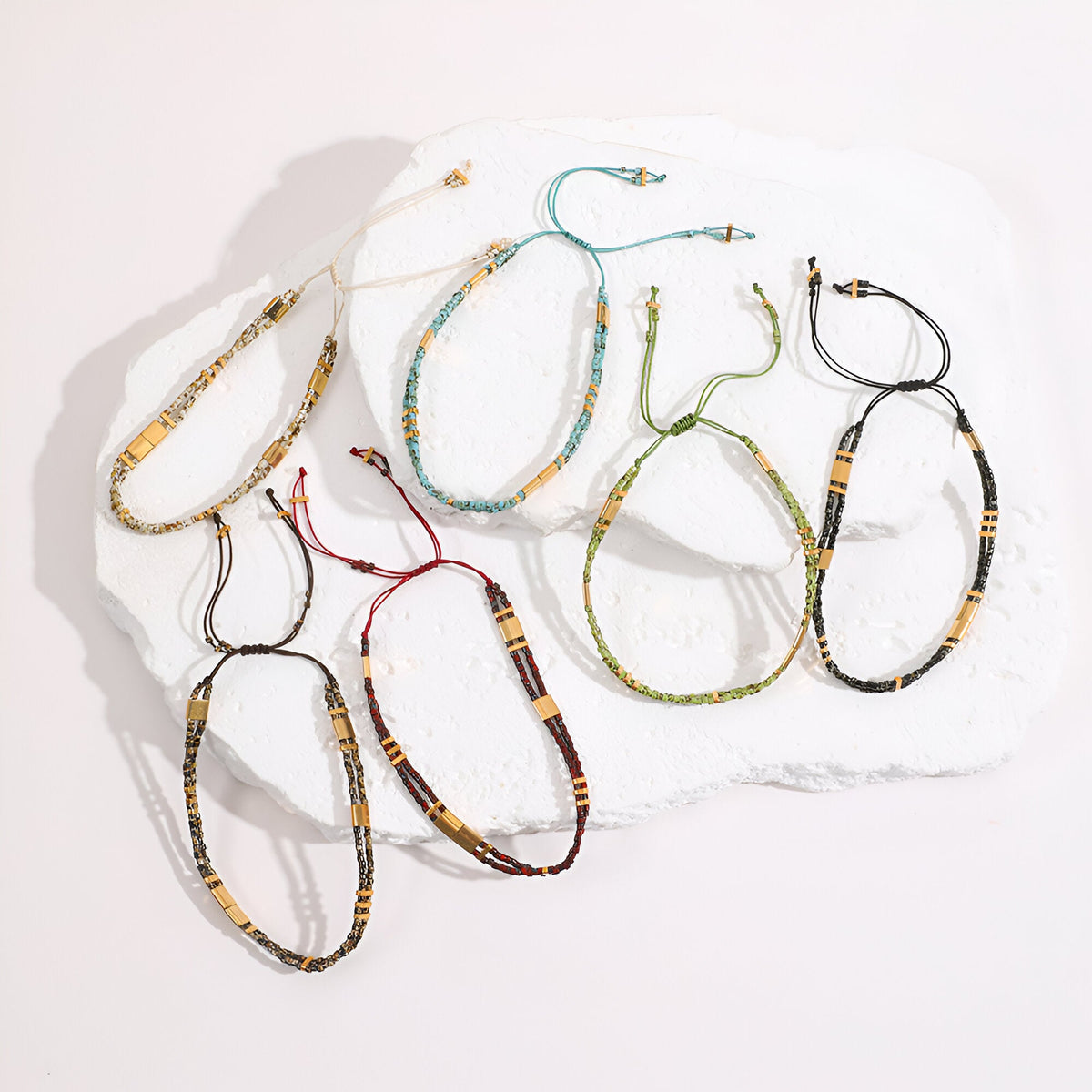 Set de sept bracelets double-rangs ajustables en perles du Japon coloris beige, noir, bleu, bordeaux, marron et vert.