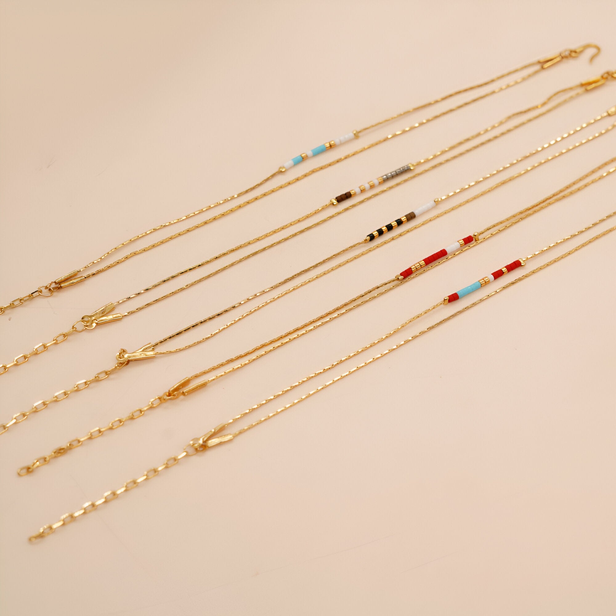 Bracelet double-rangs en perles rouges, bleues et blanches avec chaînes fines dorées.