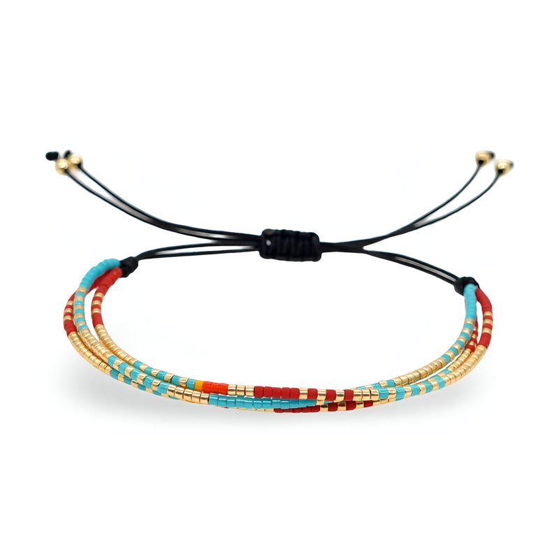 Bracelet multi-rangs en perles rouges, turquoise et dorées sur cordon noir réglable.