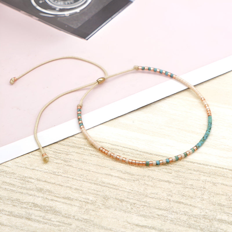 Bracelet en perles turquoise et cuivrées, cordon beige ajustable, style délicat et féminin.