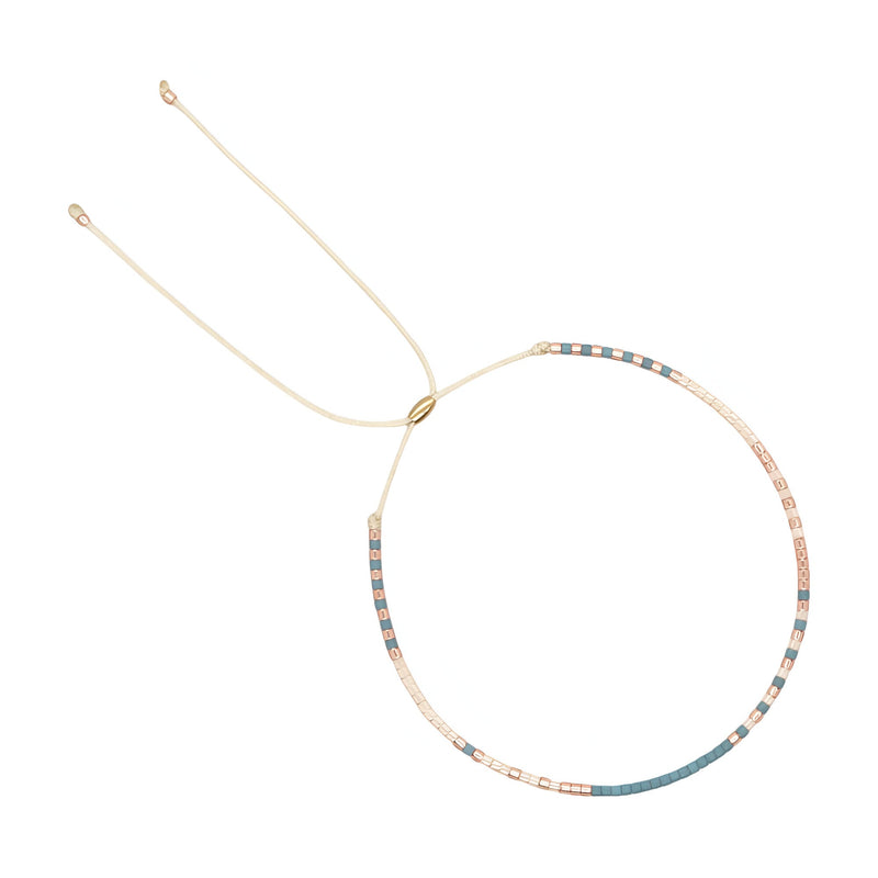 Bracelet fin avec petites perles turquoise et pêche alternées sur fil beige ajustable.