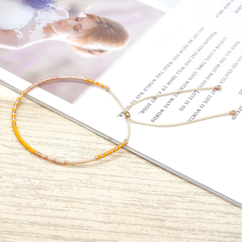 Bracelet en perles japonaises fines dégradé orange et beige avec fermoir coulissant or rose.