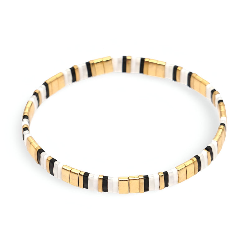 Bracelet fin en perles dorées, blanches et noires, style minimaliste et élégant.