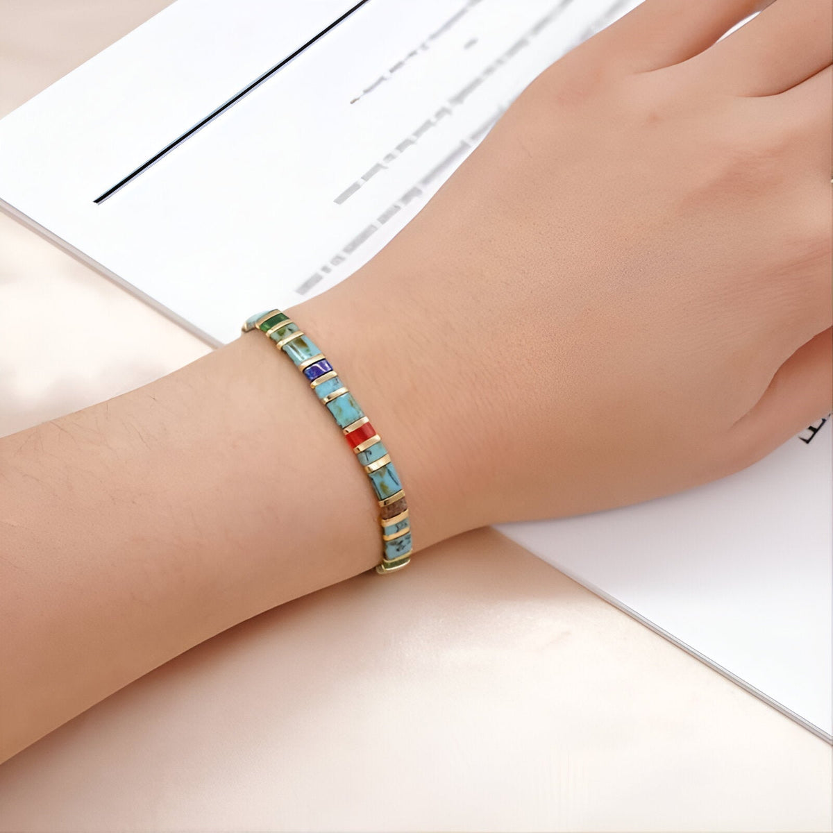Bracelet ajusté en perles carrées multicolores bleu, vert et orange sur poignet féminin.