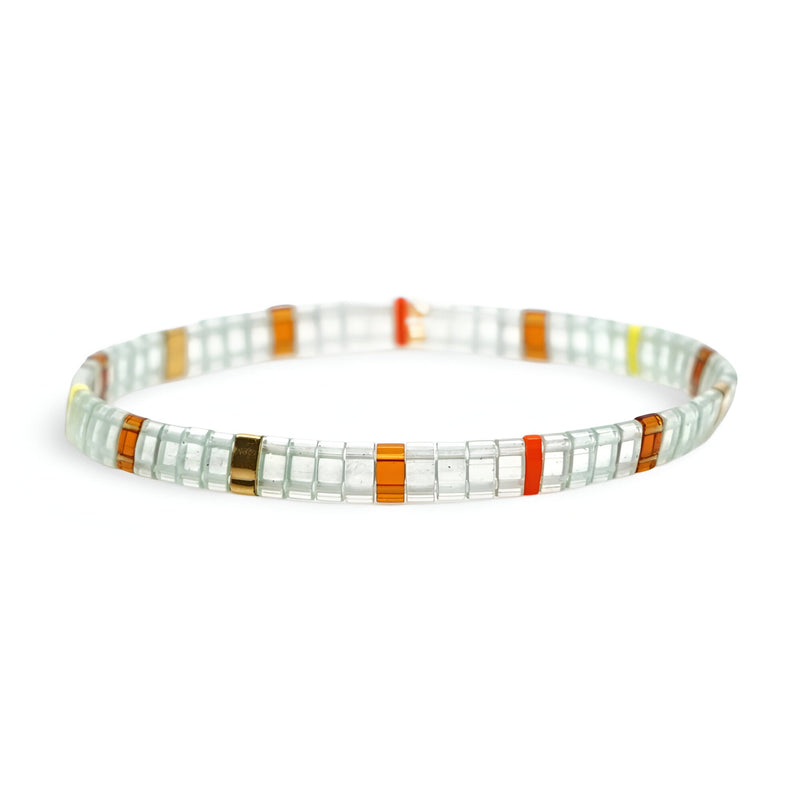 Bracelet féminin en perles japonaises blanches avec accents orange, rouge et vert, motif géométrique délicat.