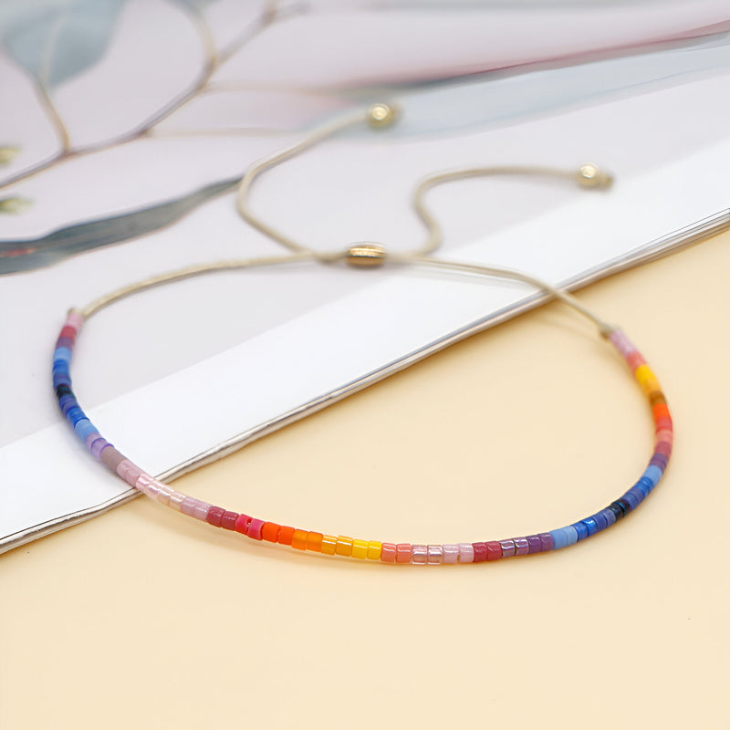 Bracelet fin réglable en perles japonaises multicolores style Kumiko sur fond neutre.