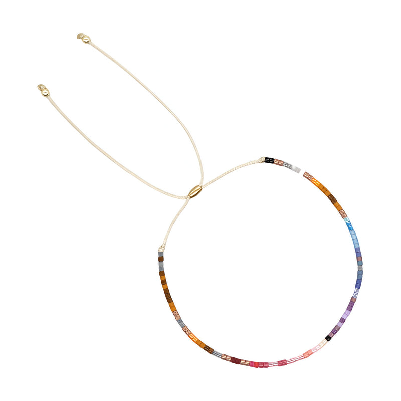 Bracelet fin à perles japonaises multicolores en dégradé sur fil doré ajustable.