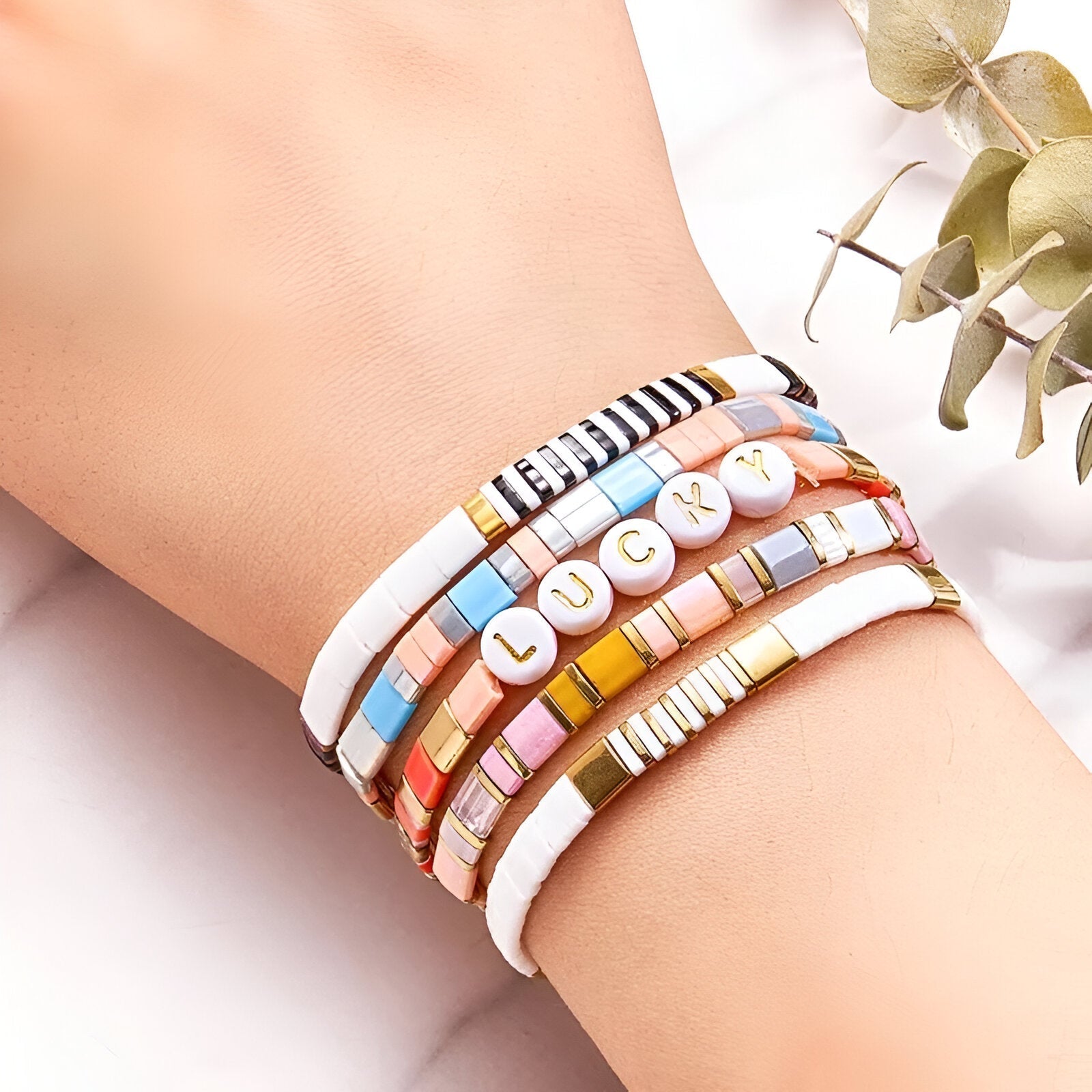 Bracelet multi-rangs en perles colorées et lettres blanches formant "LOVE" sur poignet féminin.