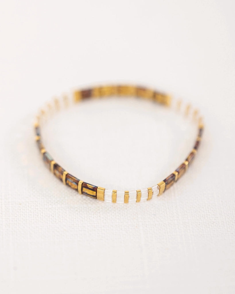 Bracelet fin marron avec perles japonaises alternant sections dorées et transparentes.
