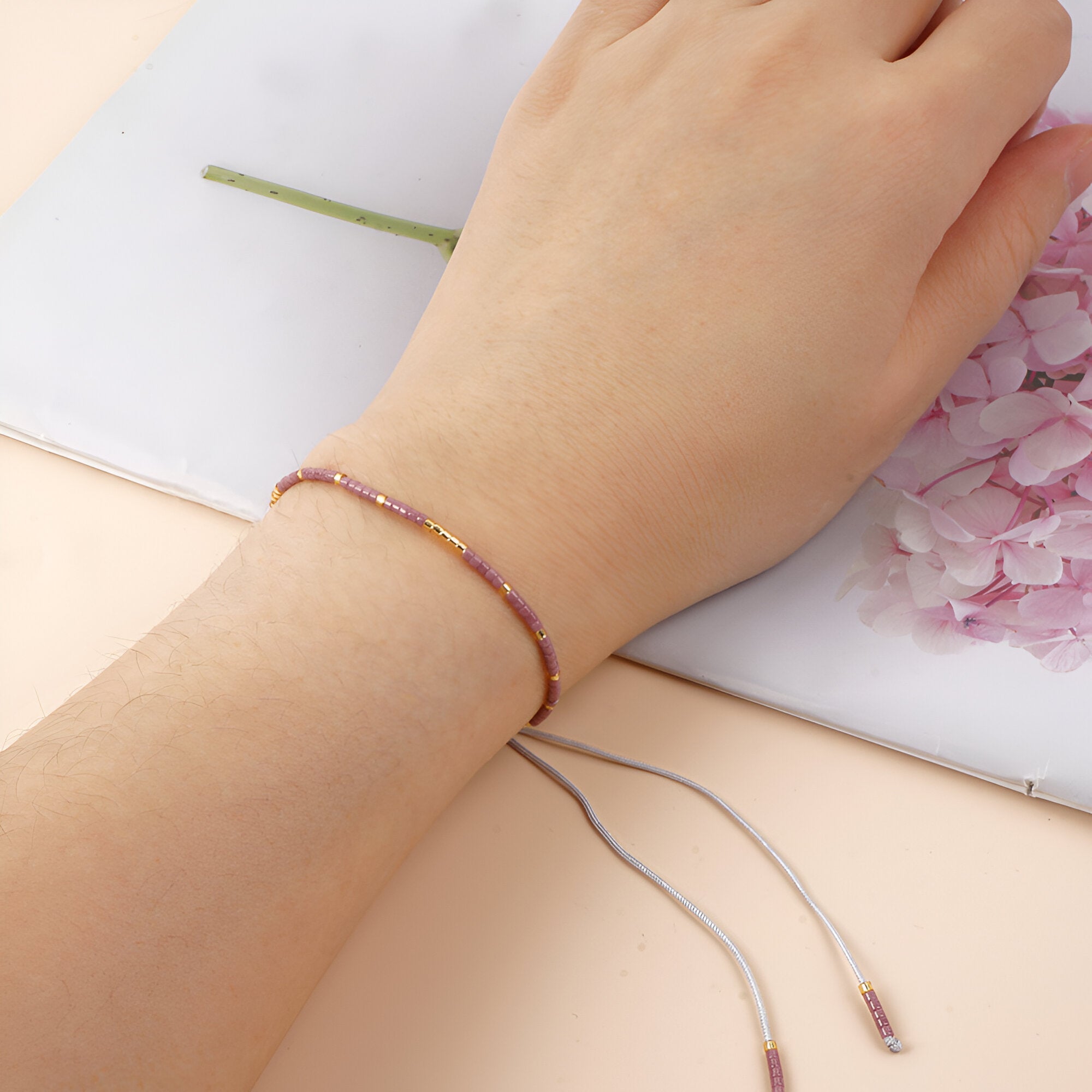 Bracelet fin en perles violettes avec fermoir coulissant ajustable pour femme.