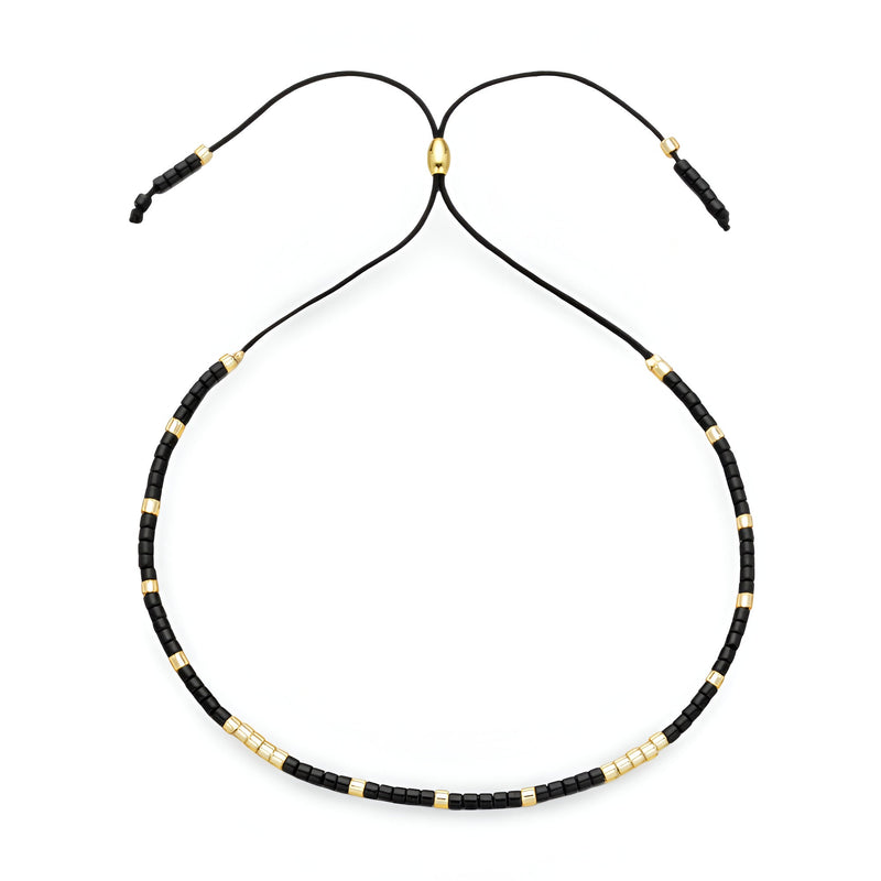 Bracelet Tsunada pour femme en perles noires et dorées sur cordon noir réglable.