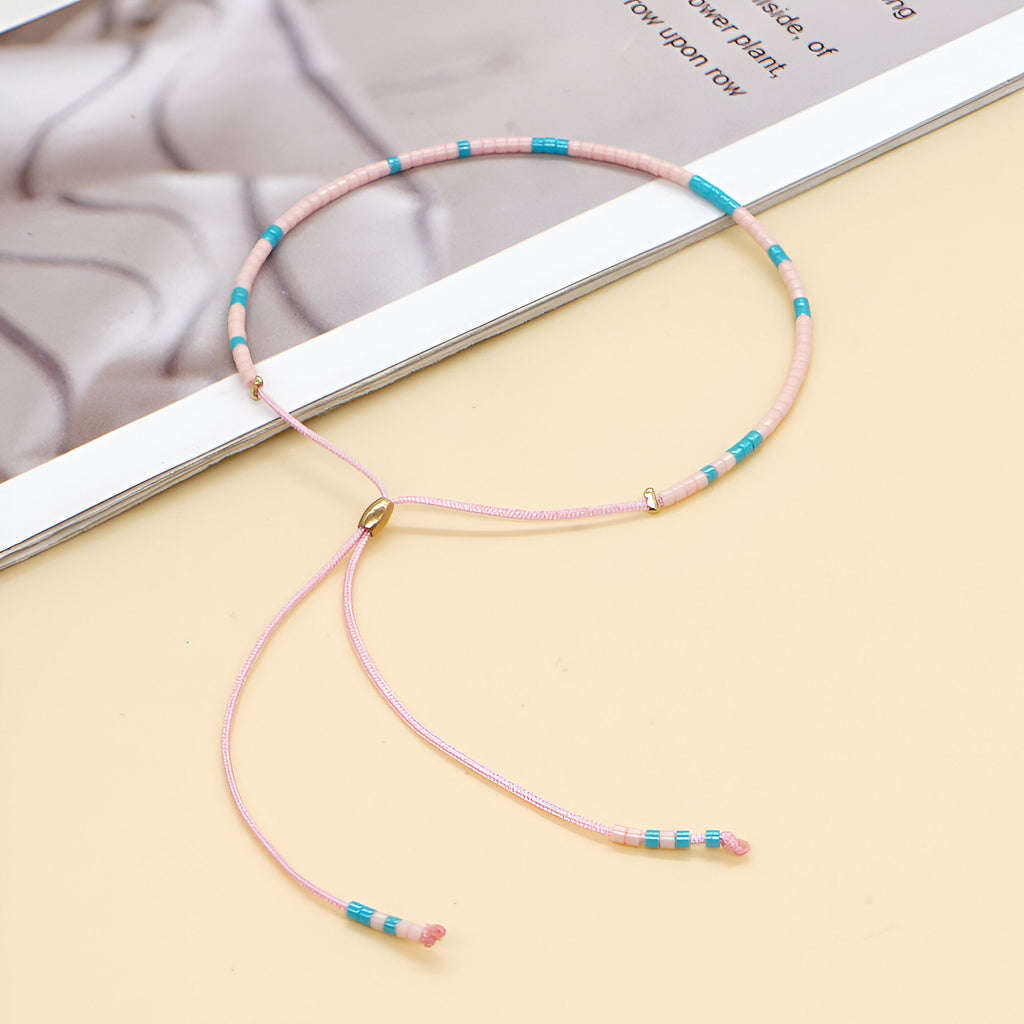 Bracelet fin en perles turquoise, rose et or avec fermeture coulissante ajustable.