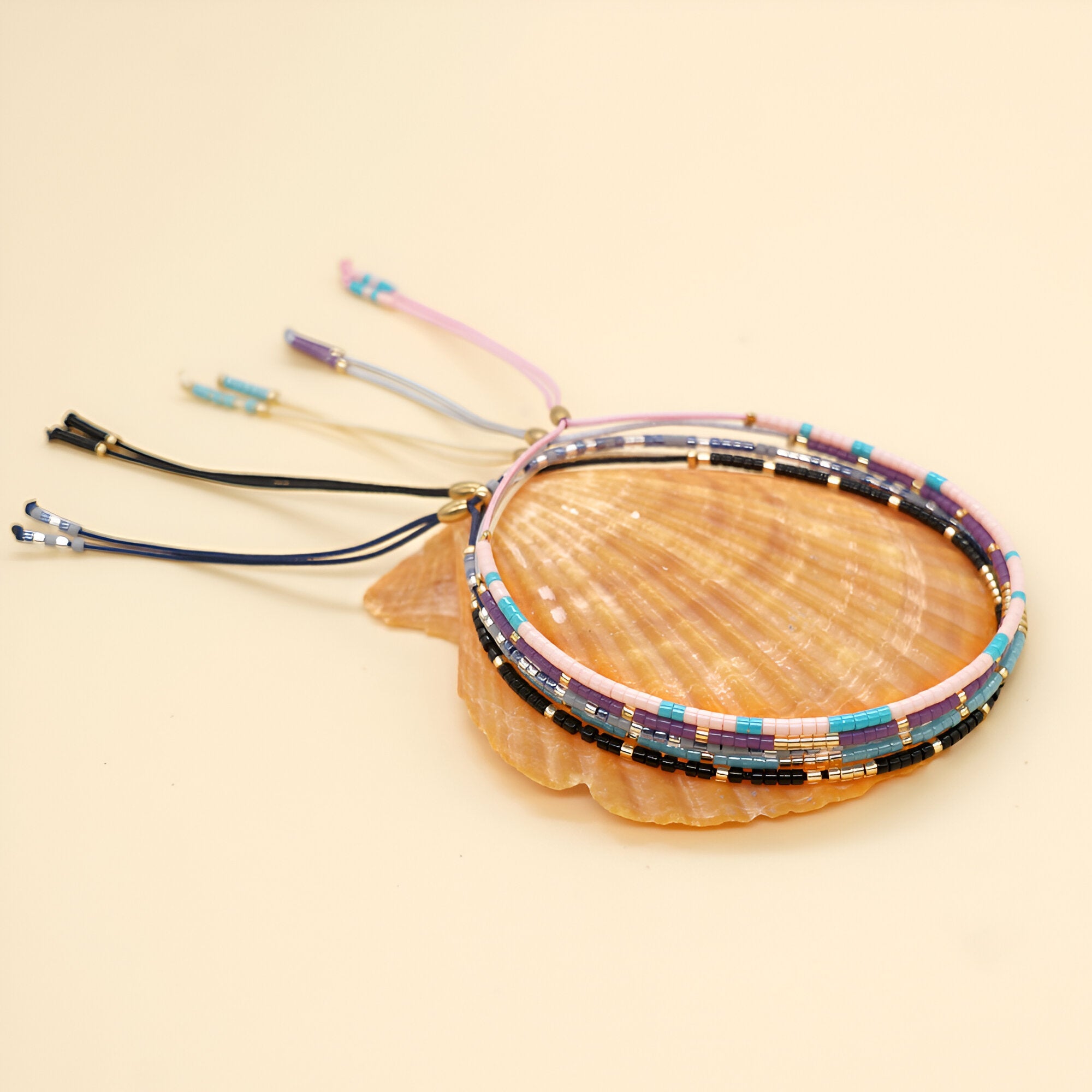 Bracelets en perles japonaises multicolores avec cordons ajustables en noir, violet et rose.