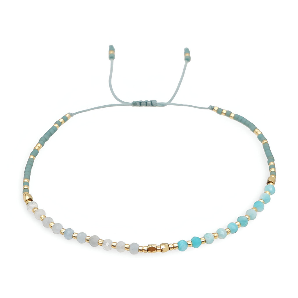 Bracelet fin en perles heishi turquoise et blanches avec détails dorés et cordon ajustable gris clair.
