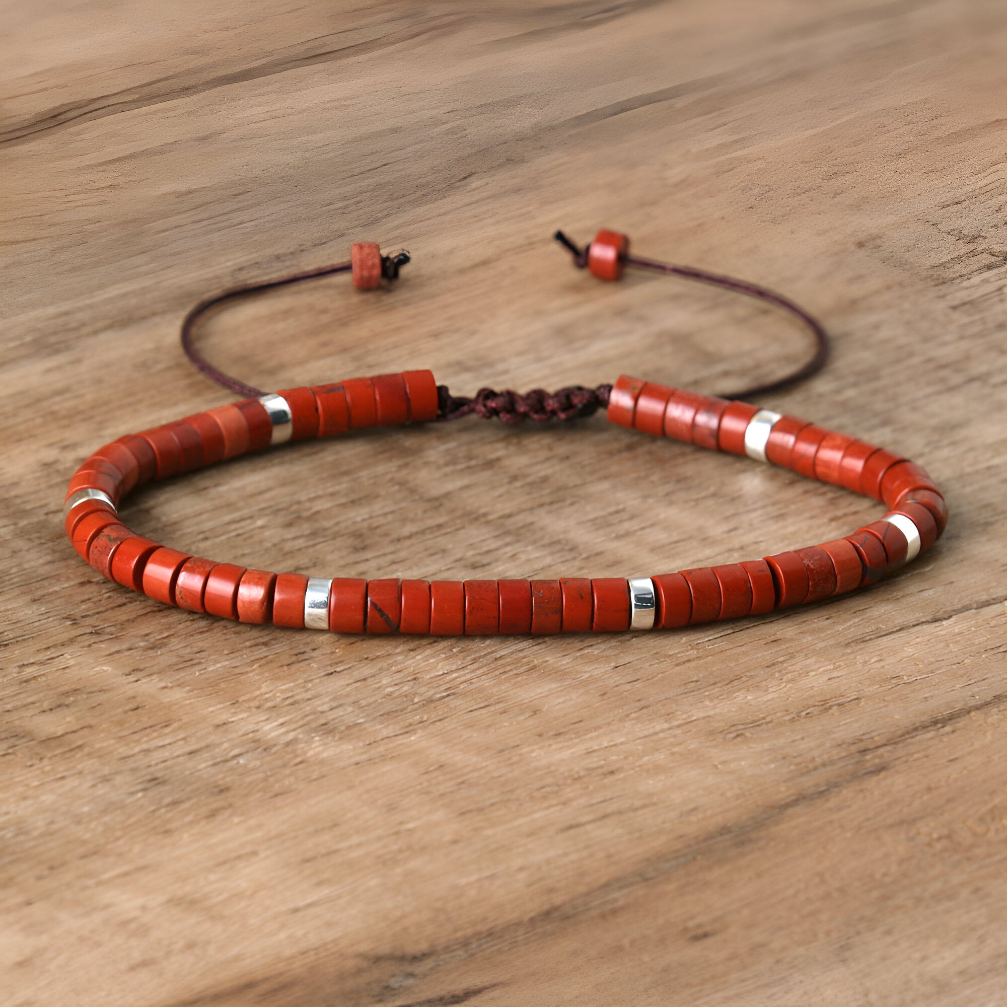Bracelet mixte en perles heishi jaspe rouge avec anneaux métalliques argentés et cordon ajustable brun.