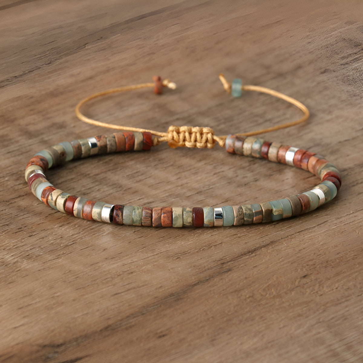 Bracelet mixte en perles heishi multicolores avec détails métalliques dorés sur cordon rigide.