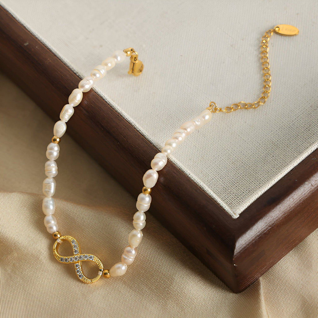 Bracelet en perles naturelles blanches avec motif infini en or serti de zircones brillantes.