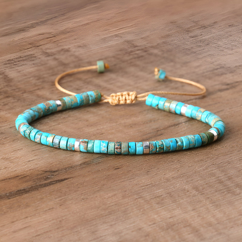 Bracelet mixte en perles heishi bleu turquoise avec fermoir doré réglable sur fond bois.