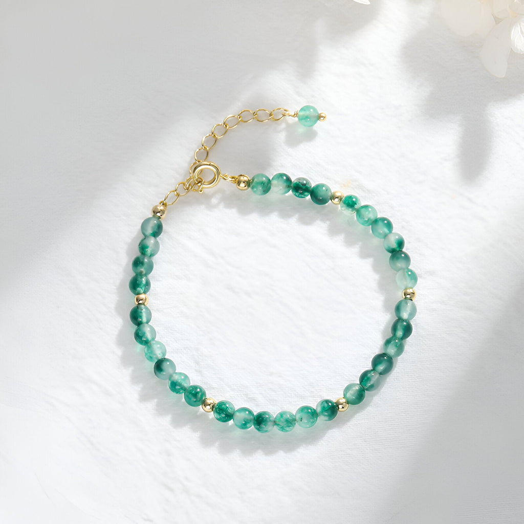 Bracelet pour femme en perles d'agate vertes translucides et petits détails en métal doré, fermoir réglable.