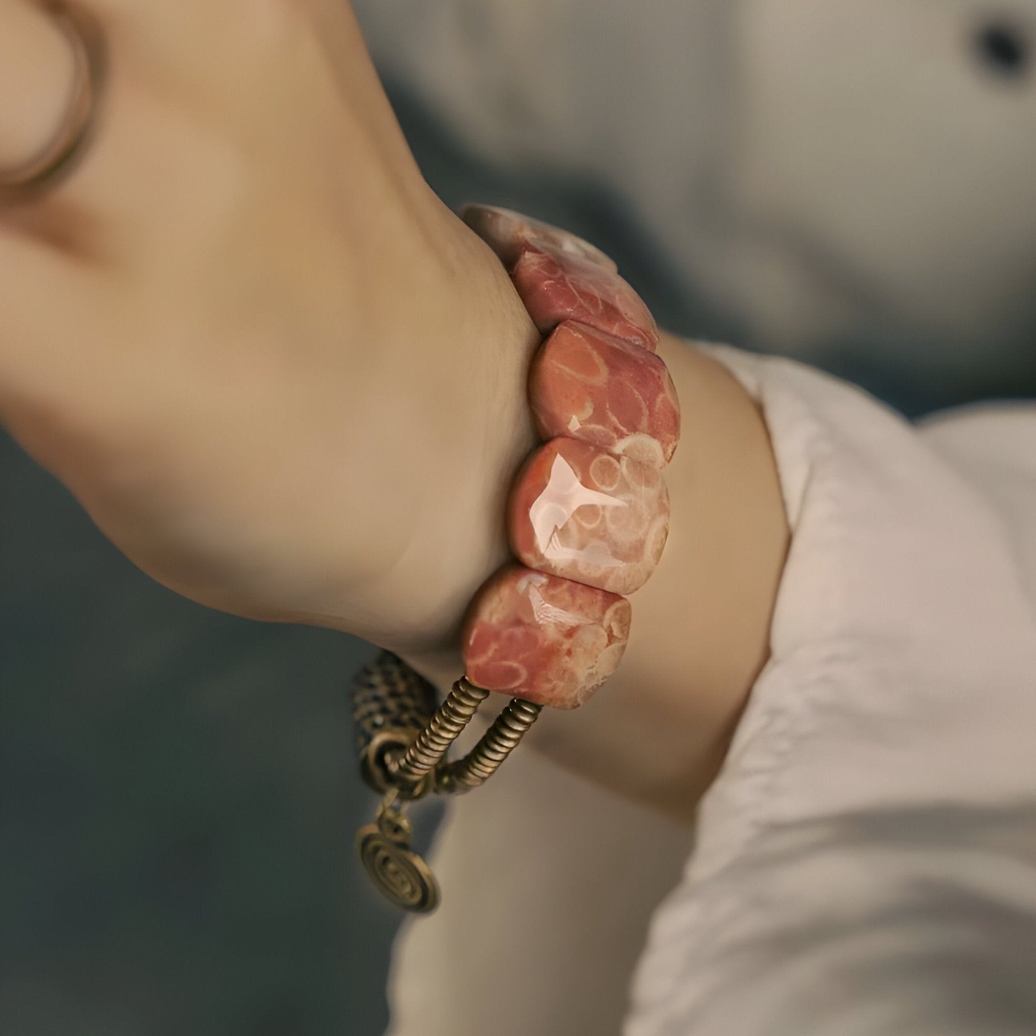 Bracelet femme en pierre de corail orange polie avec fermoir en cuivre texturé, style artisanal.