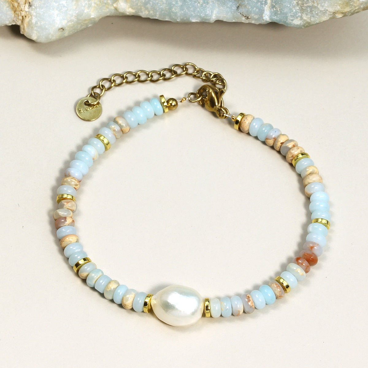 Bracelet femme perles multicolores pastel avec perle nacrée centrale et fermoir doré ajustable.