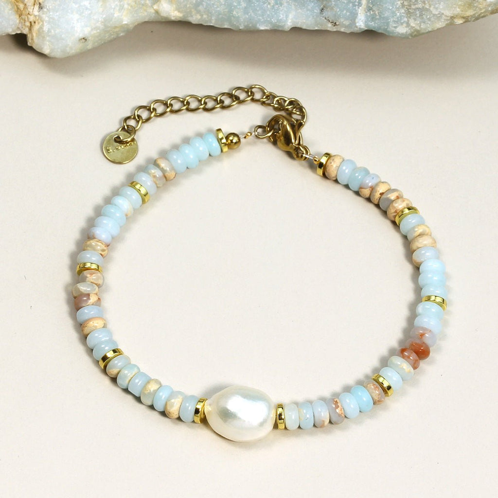 Bracelet femme perles multicolores pastel avec perle nacrée centrale et fermoir doré ajustable.