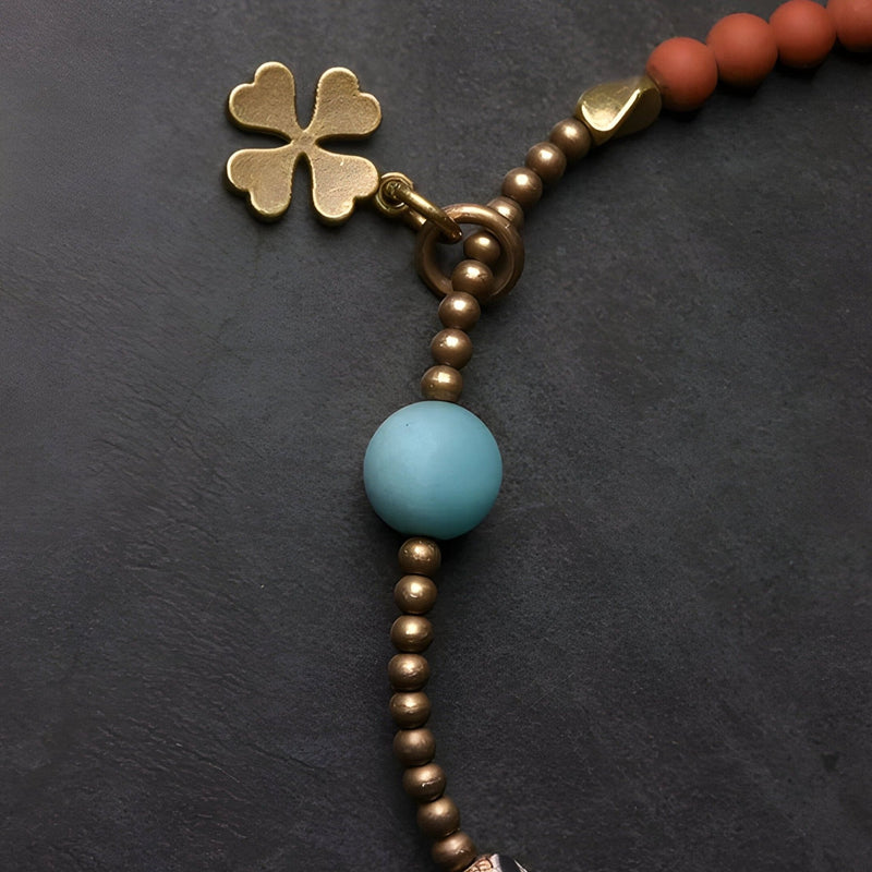 Bracelet femme avec perles métalliques bronze, perle agate bleue, breloque trèfle doré.